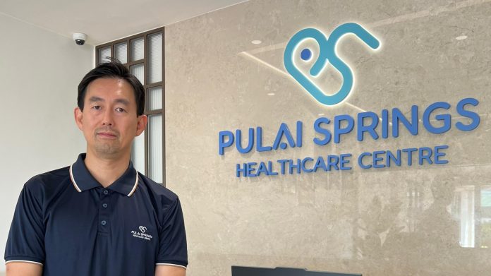 20250805_163046 Nick Mah Siew Chean, Executive Director of Pulai Group, standing in front of Pulai Springs Healthcare Centre signage